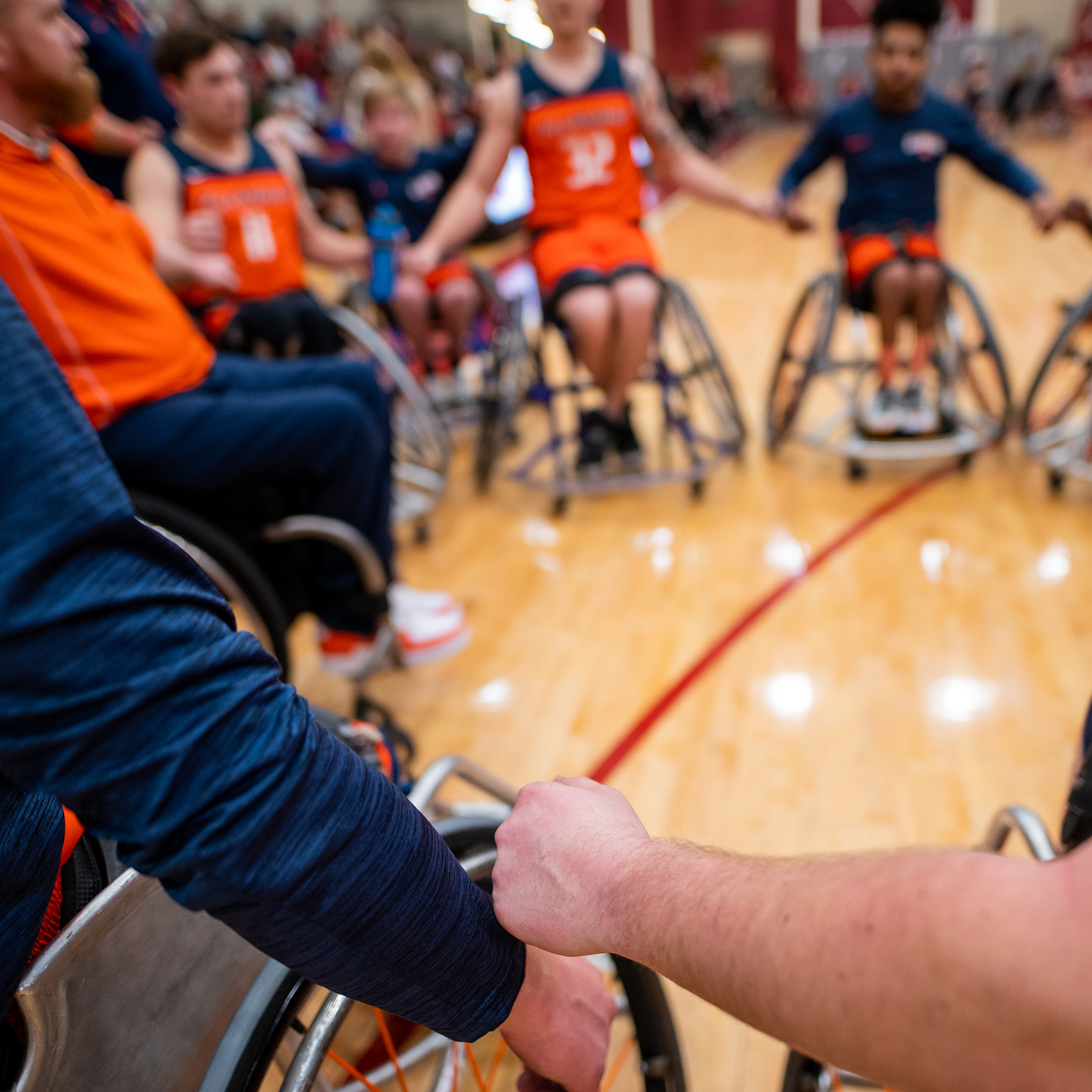 Illini wheelchair basketball team huddled in a circle on the court.