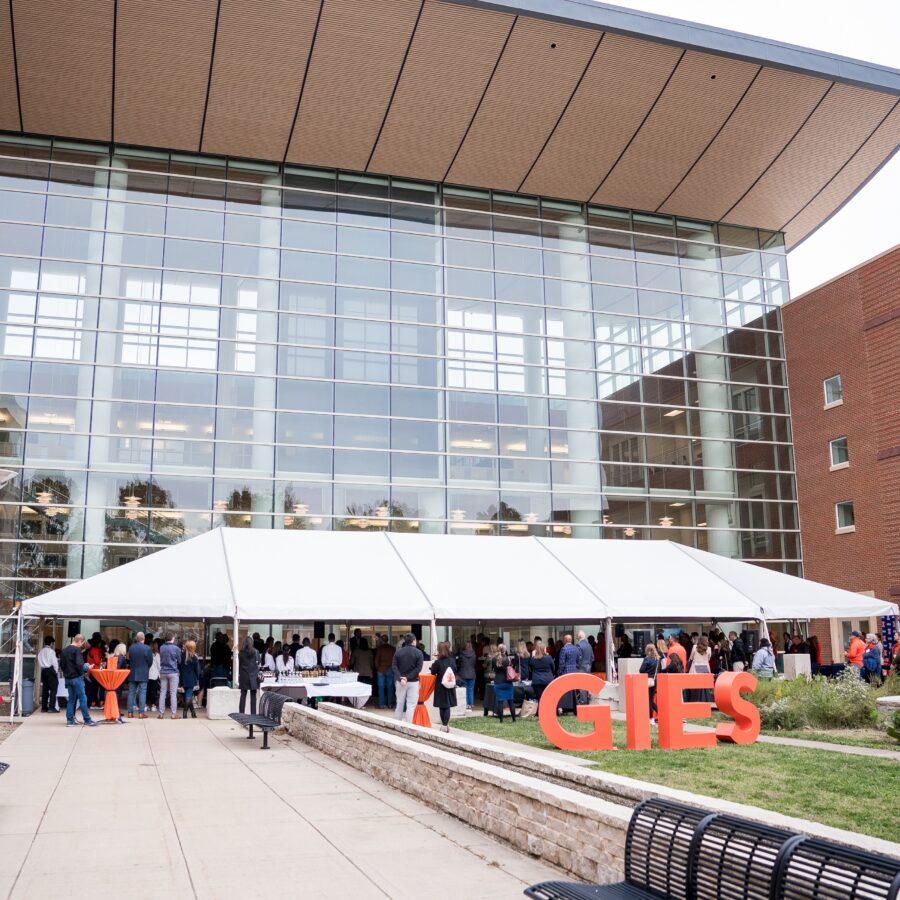 Alumni, friends, students, faculty, and staff celebrating the With Illinois Campaign under a tent outside of the Gies Business building.