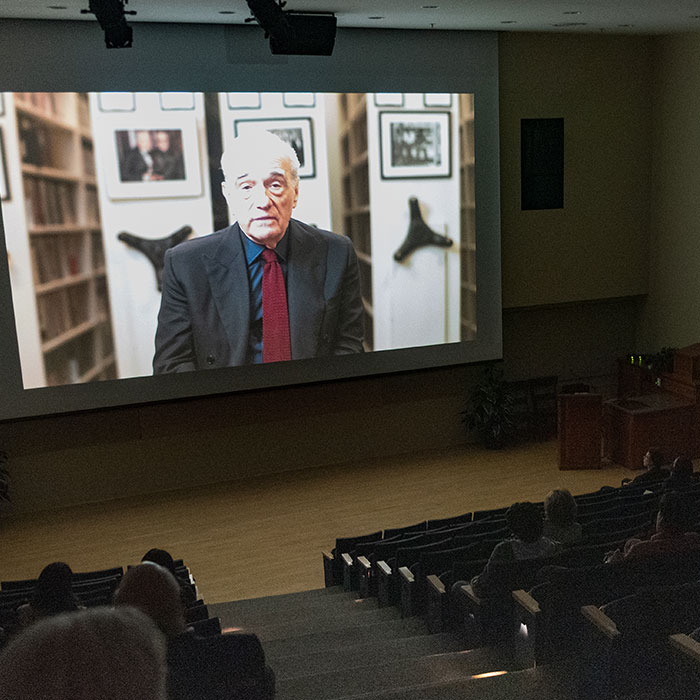 Students watching martin scorsese on a projector in a lecture hall.
