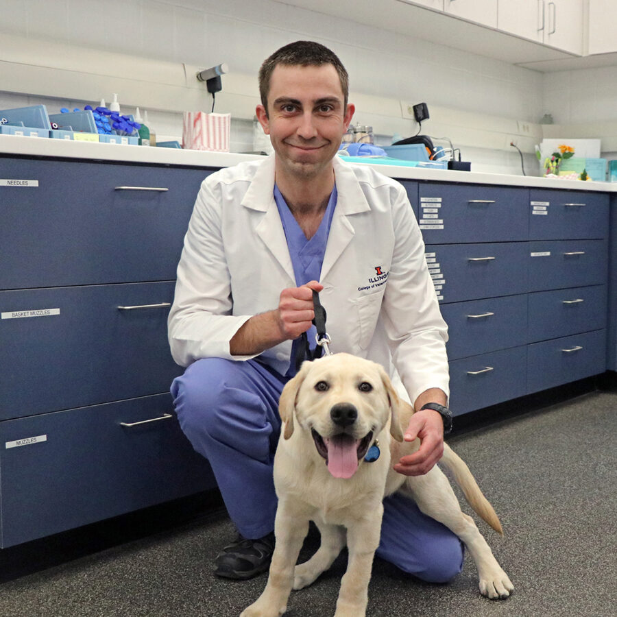 Dr. Tatnall smiling in his office with one of his canine patients.
